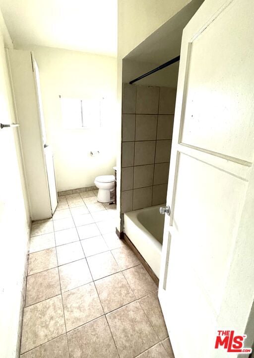 bathroom with tile patterned floors, tiled shower / bath combo, and toilet