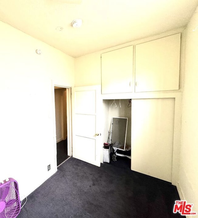 unfurnished bedroom featuring a closet and dark colored carpet