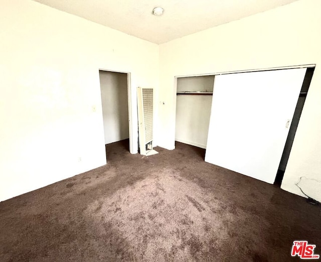 unfurnished bedroom featuring dark colored carpet and a closet