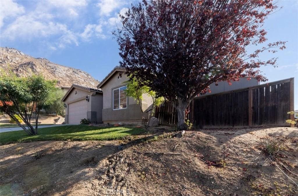 view of home's exterior with a lawn, a mountain view, and a garage