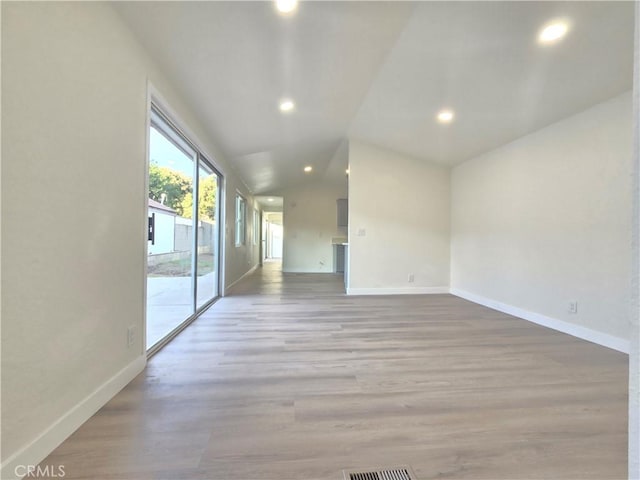 empty room with light wood-type flooring and lofted ceiling