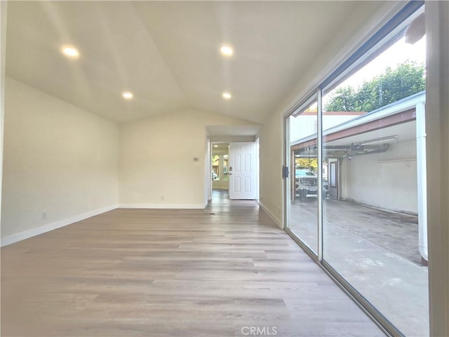 spare room with light hardwood / wood-style floors and vaulted ceiling