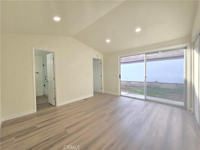 unfurnished room with vaulted ceiling and light wood-type flooring