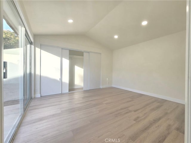 empty room featuring light wood-type flooring and vaulted ceiling