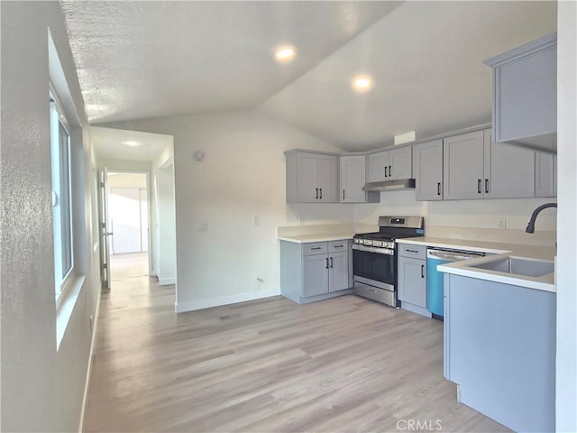 kitchen with appliances with stainless steel finishes, sink, plenty of natural light, gray cabinets, and light hardwood / wood-style flooring