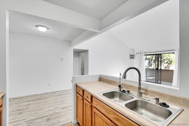 kitchen with light wood-type flooring, sink, and vaulted ceiling