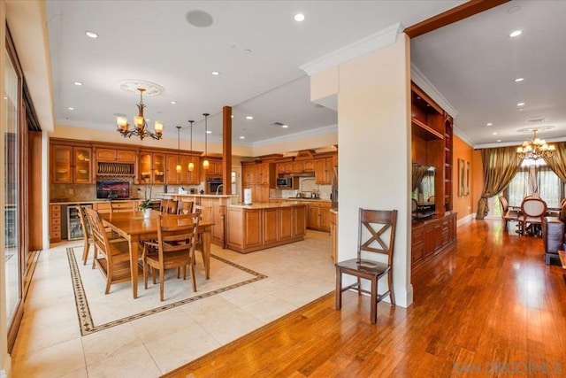 dining space with light hardwood / wood-style flooring, beverage cooler, and an inviting chandelier