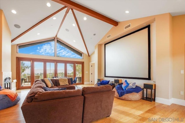 cinema room with beamed ceiling, light wood-type flooring, and high vaulted ceiling