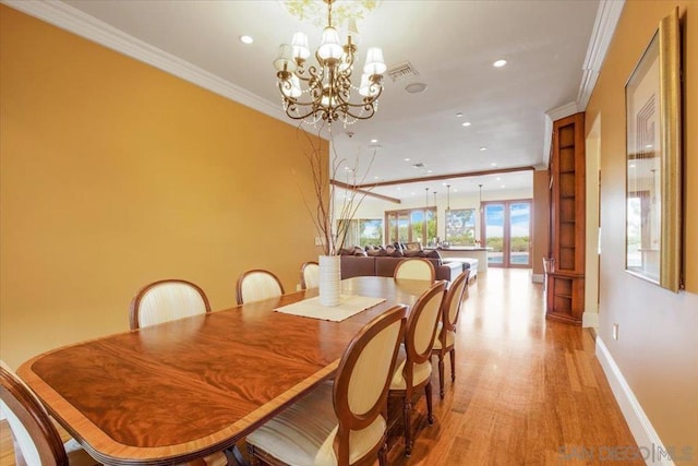 dining space featuring a chandelier, light wood-type flooring, and crown molding