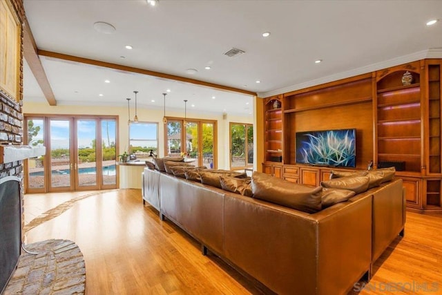 living room featuring a fireplace, french doors, light hardwood / wood-style floors, and built in shelves