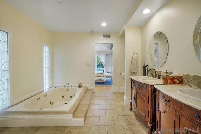 bathroom featuring vanity, a healthy amount of sunlight, and tiled tub