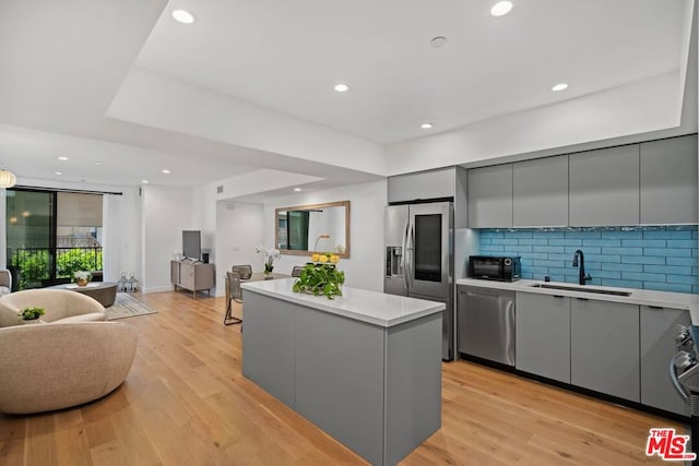 kitchen featuring sink, a center island, light hardwood / wood-style flooring, gray cabinets, and appliances with stainless steel finishes