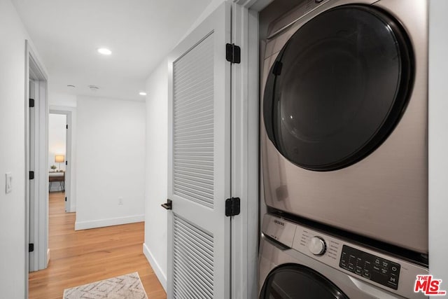 clothes washing area with light hardwood / wood-style floors and stacked washing maching and dryer