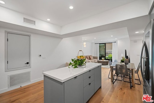 kitchen with stainless steel fridge, light wood-type flooring, and gray cabinetry