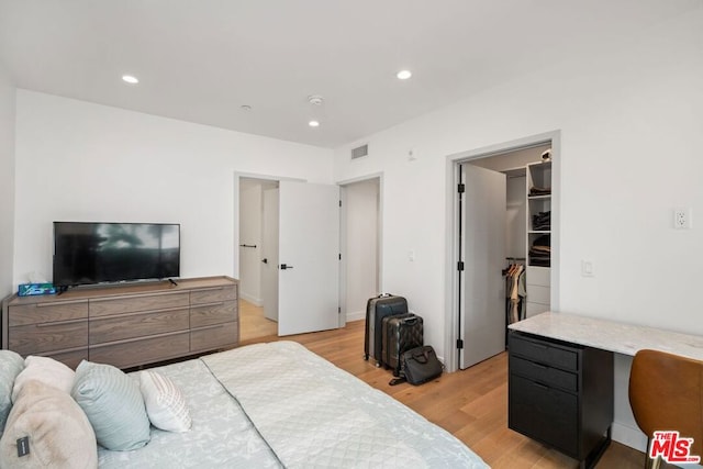 bedroom featuring a walk in closet, light hardwood / wood-style flooring, and a closet