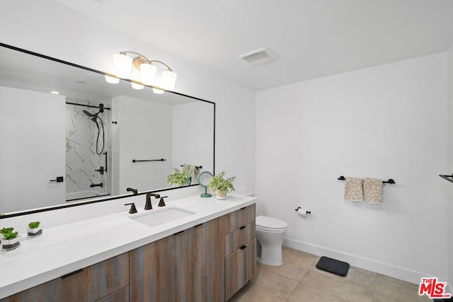 bathroom with tiled shower, vanity, tile patterned floors, and toilet