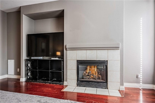 room details with a tile fireplace, baseboards, and wood finished floors