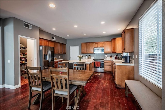 kitchen with visible vents, a kitchen island, dark wood-style flooring, light countertops, and appliances with stainless steel finishes