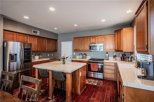 kitchen with tile counters, visible vents, stainless steel appliances, and a sink