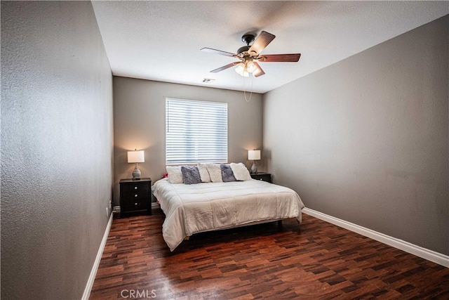 bedroom with visible vents, wood finished floors, baseboards, ceiling fan, and a textured wall