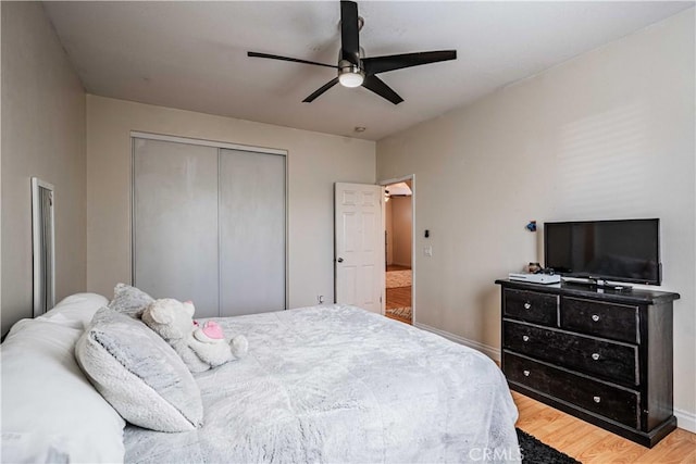 bedroom with a closet, baseboards, a ceiling fan, and wood finished floors