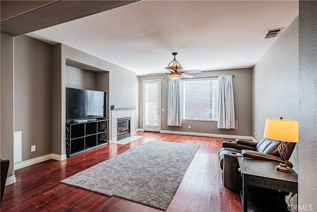 living room with hardwood / wood-style floors, a ceiling fan, baseboards, visible vents, and a fireplace