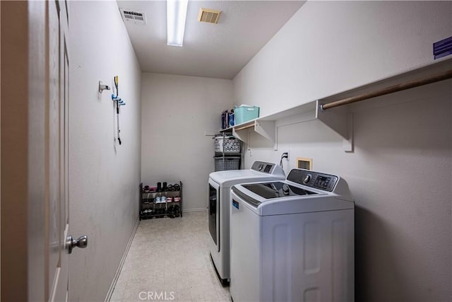 clothes washing area with visible vents, separate washer and dryer, light floors, and laundry area