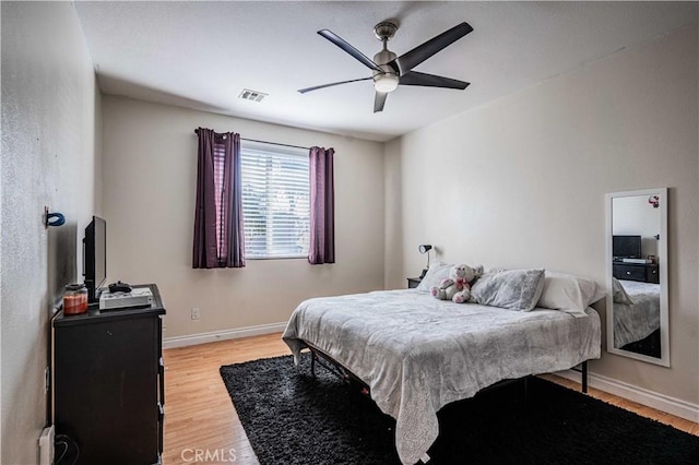 bedroom with visible vents, baseboards, a ceiling fan, and light wood finished floors