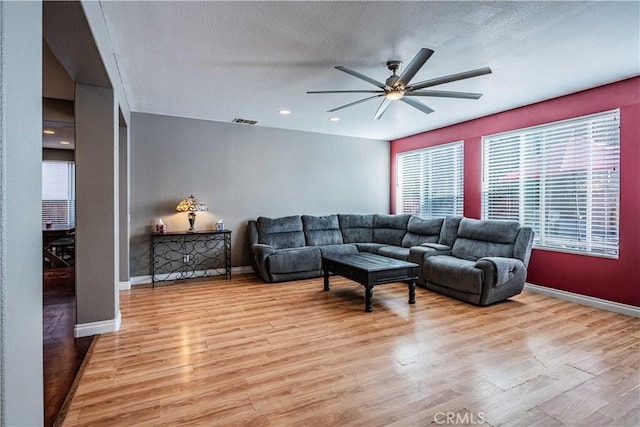 living area with a textured ceiling, wood finished floors, visible vents, and baseboards