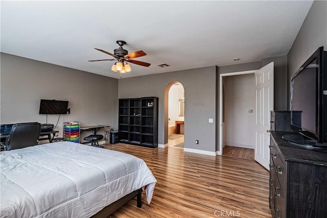 bedroom featuring visible vents, arched walkways, light wood finished floors, baseboards, and ceiling fan