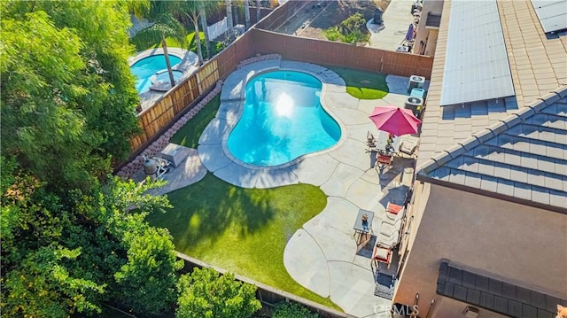 community pool with a patio area, a fenced backyard, and a hot tub