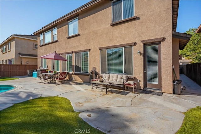 rear view of property featuring stucco siding, a patio, a fenced backyard, and an outdoor hangout area