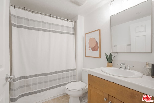 bathroom with tile patterned flooring, vanity, curtained shower, and toilet