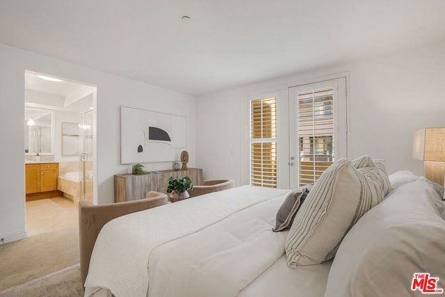 bedroom with ensuite bathroom and light colored carpet