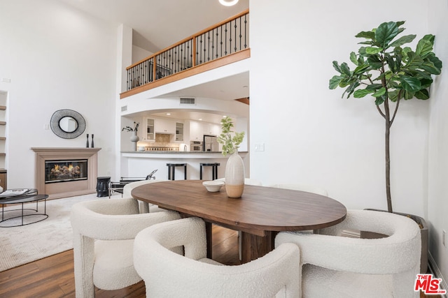 dining space with wood-type flooring and a high ceiling