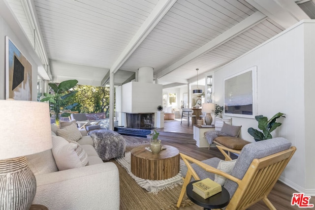 living room featuring a multi sided fireplace, dark hardwood / wood-style flooring, and lofted ceiling with beams