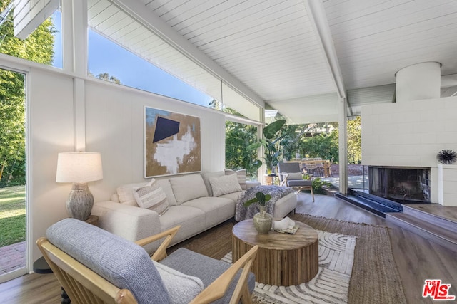 sunroom with lofted ceiling with beams and a tiled fireplace