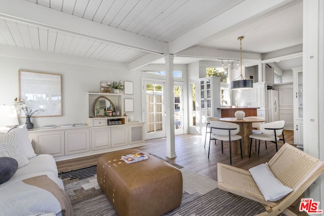 living room with decorative columns, hardwood / wood-style floors, and beamed ceiling