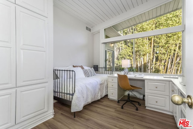 bedroom featuring lofted ceiling with beams, dark hardwood / wood-style floors, and multiple windows