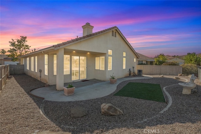 back house at dusk featuring central AC and a patio area