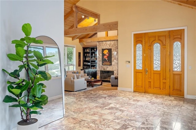 foyer entrance featuring high vaulted ceiling, a fireplace, baseboards, marble finish floor, and beam ceiling