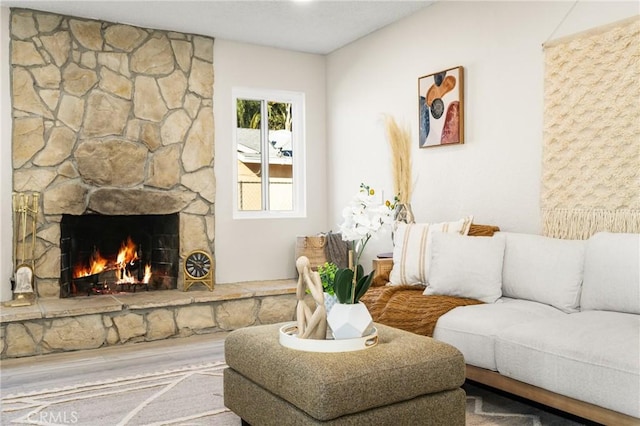 living room featuring wood-type flooring and a stone fireplace