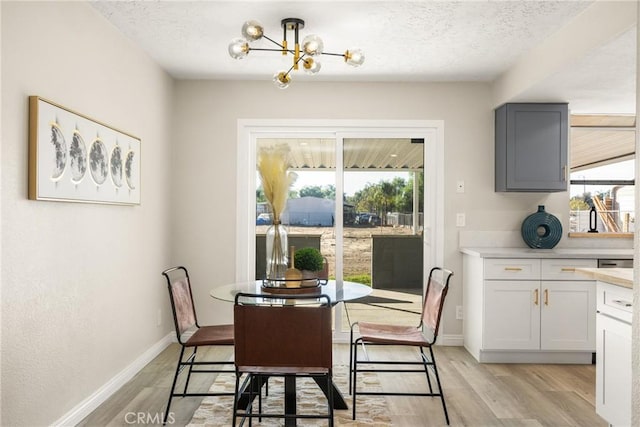 dining space featuring light hardwood / wood-style floors, a textured ceiling, and a chandelier