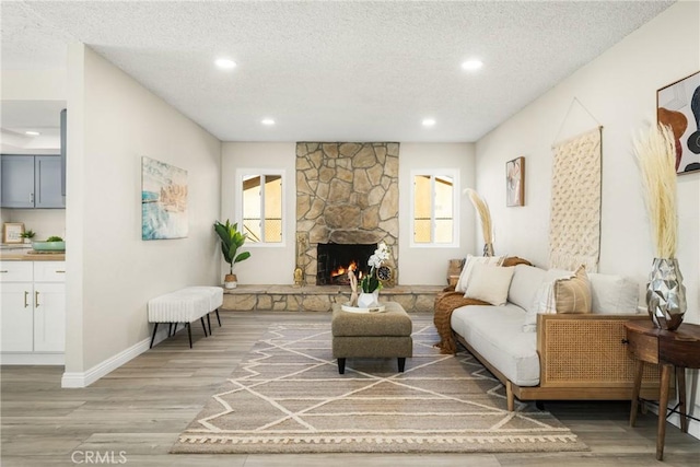 living room with a textured ceiling, light hardwood / wood-style floors, and a fireplace