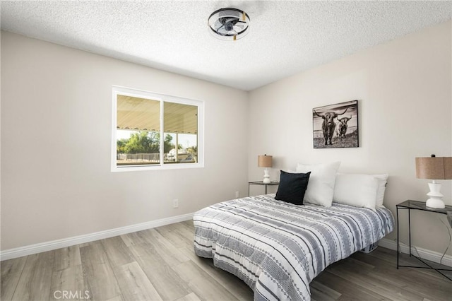 bedroom featuring light hardwood / wood-style floors and a textured ceiling