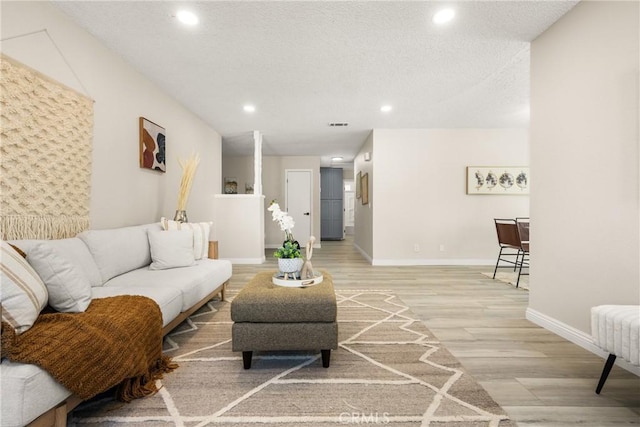 living room featuring radiator heating unit, light wood-type flooring, and a textured ceiling