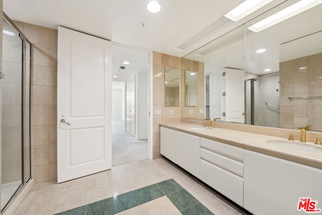 bathroom featuring tile patterned floors, a shower with door, vanity, and tile walls