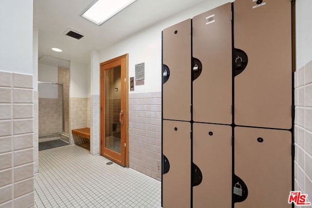 hallway featuring light tile patterned floors and tile walls