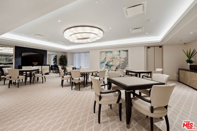 dining area with a raised ceiling and light carpet