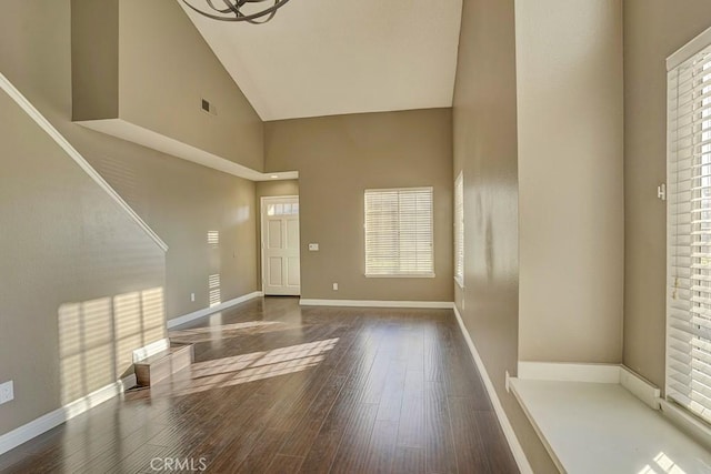 foyer with dark hardwood / wood-style floors, high vaulted ceiling, and a notable chandelier